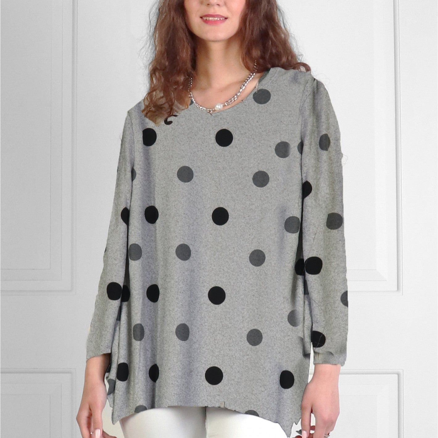 Woman wearing a gray sweater with black polka dots against a white background