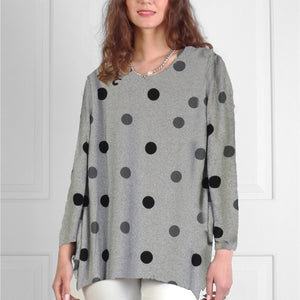 Woman wearing a gray sweater with black polka dots against a white background