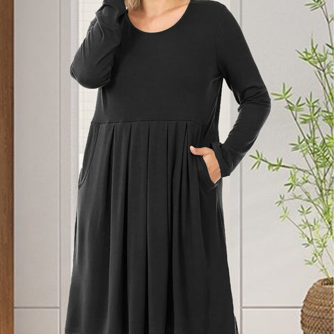 Black dress worn by a person with a white wall and plant in the background