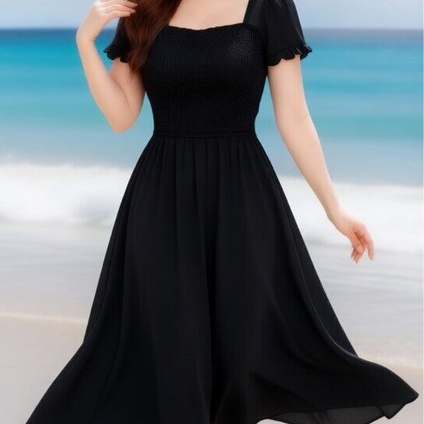 Woman wearing a black dress on a beach with ocean in the background
