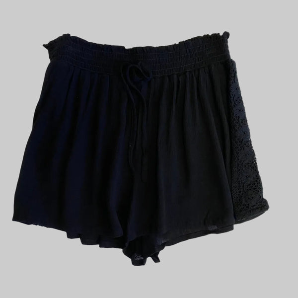 Folded black shorts on a light beige background