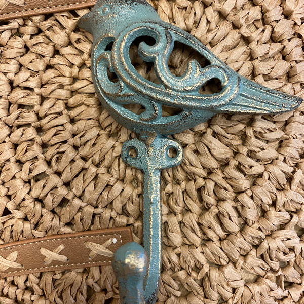 Decorative metal hook with intricate design on a textured woven surface