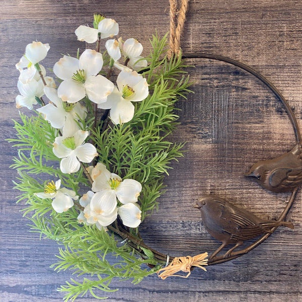 Decorative wreath with white flowers and greenery on a wooden surface