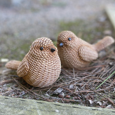 Two knitted birds sitting on a natural ground with blurred background