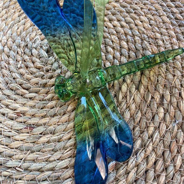 Glass dragonfly with green and blue colors on a woven mat