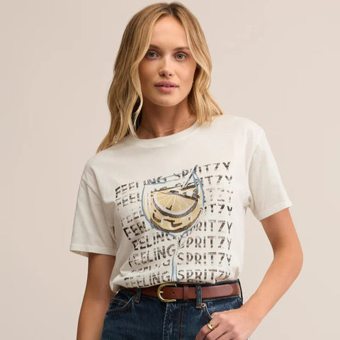 Woman wearing a graphic t-shirt and blue jeans on a beige background