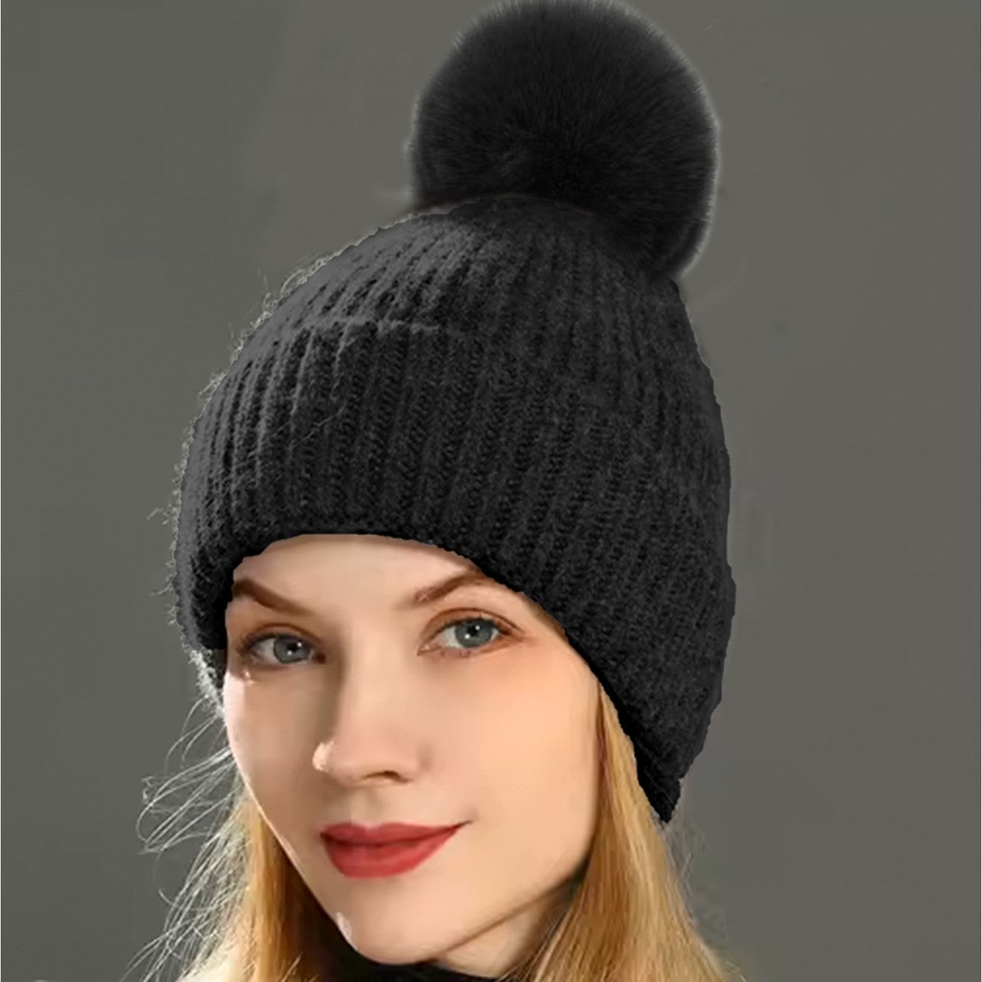 Woman wearing a black knit beanie with a pom-pom on a gray background