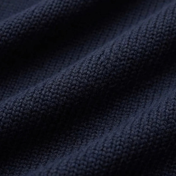 Close-up of a dark navy blue ribbed knit fabric texture with soft folds.