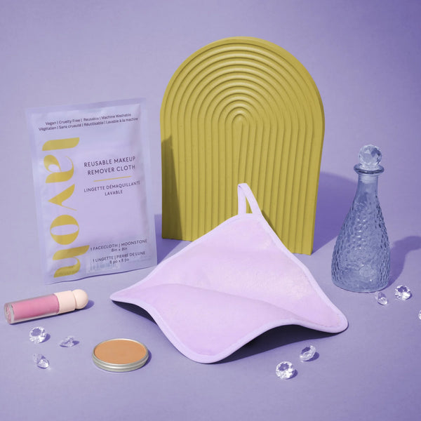 Cosmetic items including a pouch, compact, and bottle on a purple background