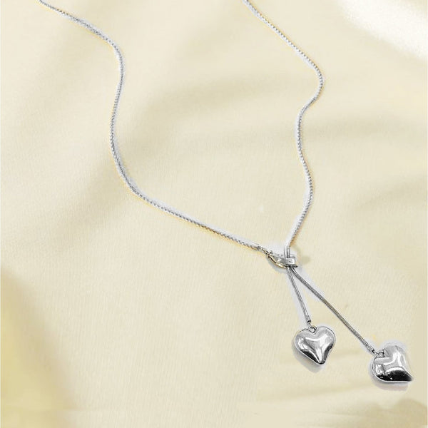 Silver heart-shaped pendant necklace on a beige background