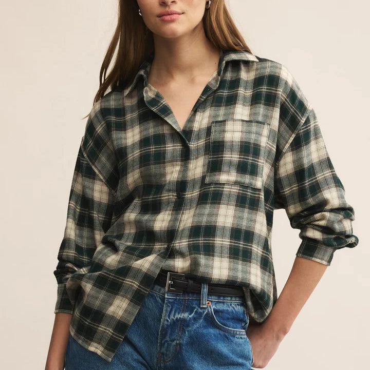 Woman wearing a plaid shirt and jeans against a beige background
