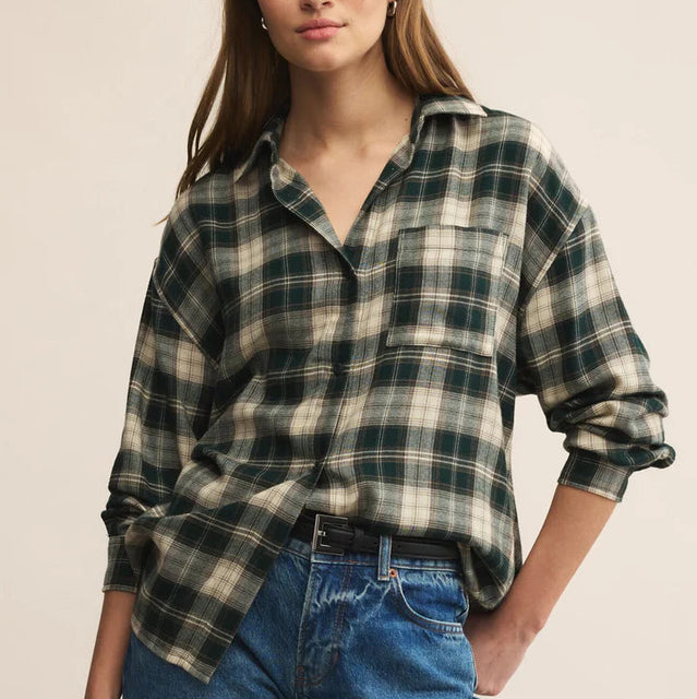 Woman wearing a plaid shirt and jeans against a beige background