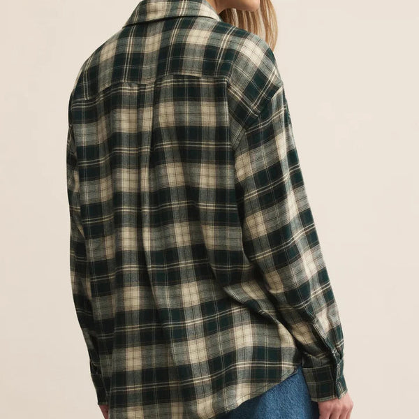 Person wearing a plaid shirt and jeans on a beige background