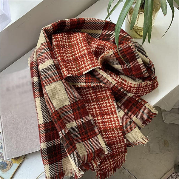 Plaid blanket with red, beige, and white pattern on a surface.