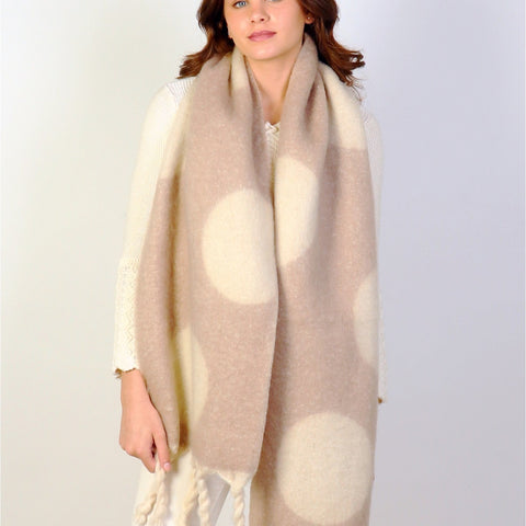 Woman wearing a beige and white polka dot scarf on a plain background