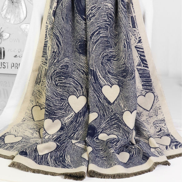 A long scarf draped on a white mannequin torso, featuring a swirling navy and beige abstract print with scattered beige hearts and fringed edges.