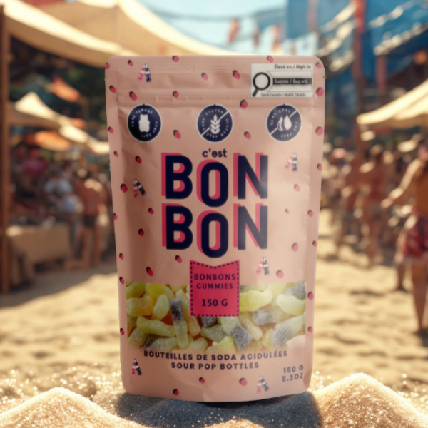 Pink packaging of 'c'est BON BON' on a sandy beach with people and umbrellas in the background.