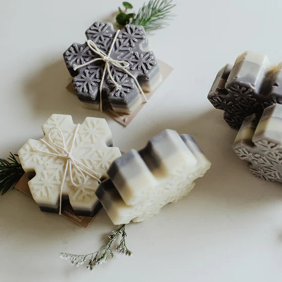 Snowflake-shaped soap bars on a white surface with greenery