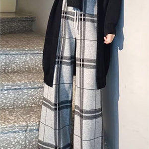 Person wearing a black coat and plaid pants standing on a staircase.
