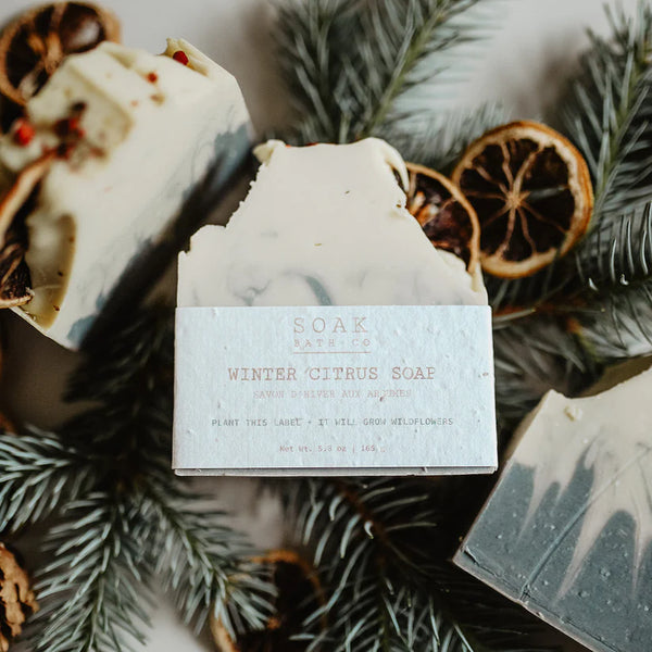 Winter citrus soap with a label on a decorative background of pine branches and dried oranges.
