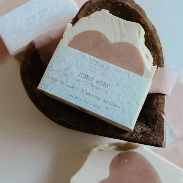 Bar of soap with a visible brand label on a natural wooden soap dish.