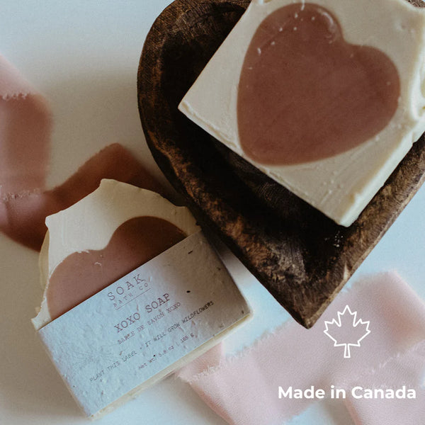 Two heart-shaped soap bars with a wooden soap dish on a light background, featuring 'Made in Canada' text.