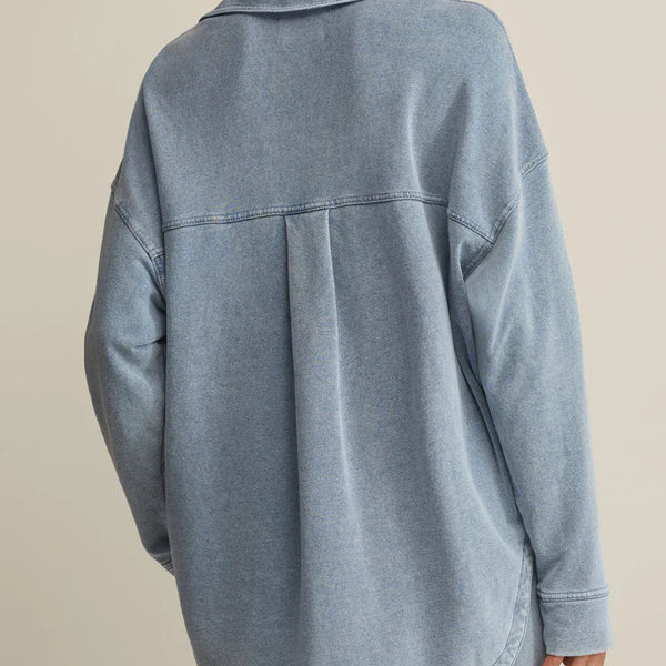 Person wearing a light blue denim jacket on a beige background