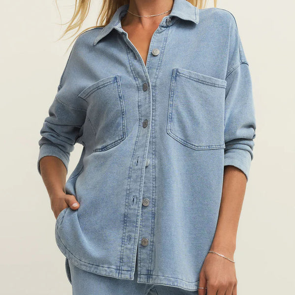 Woman wearing a light blue denim shirt against a plain background