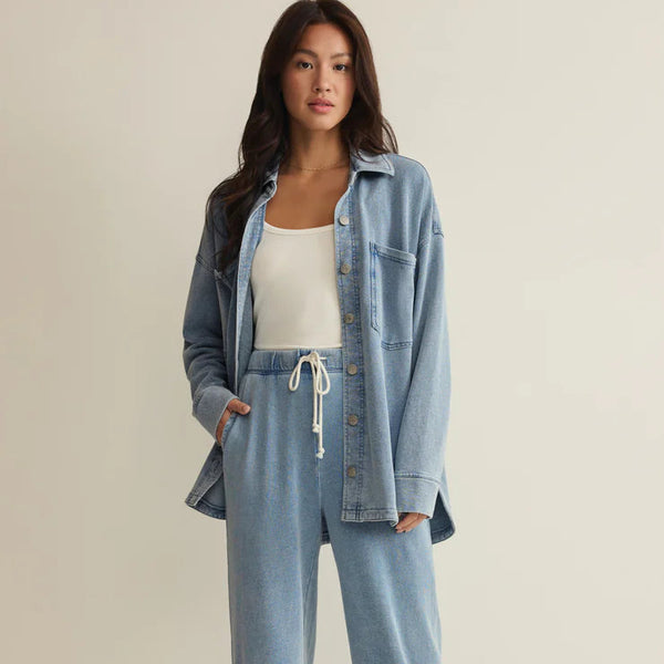 Woman wearing a denim outfit with a white top on a plain background