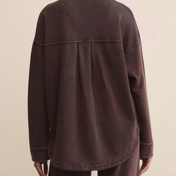 Person wearing a brown jacket and pants on a beige background