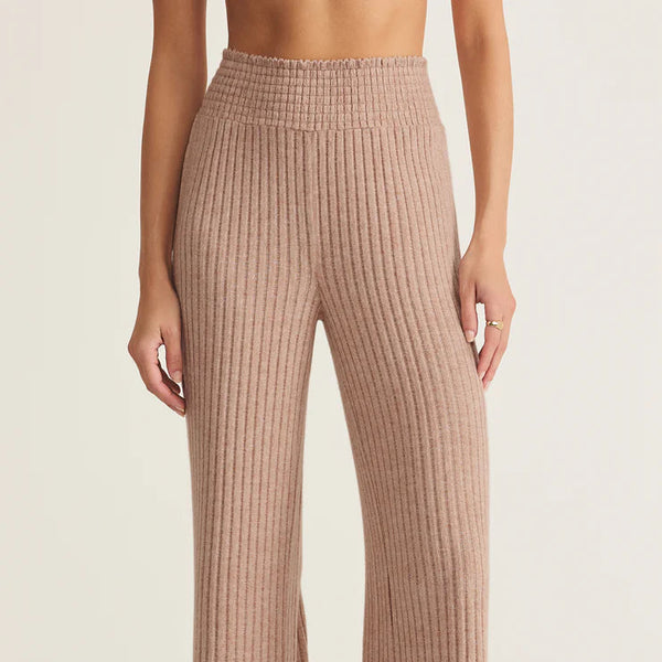 Person wearing ribbed brown pants on a beige background