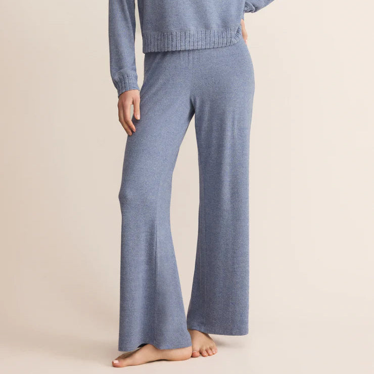 Woman wearing a blue knit sweater and pants on a beige background