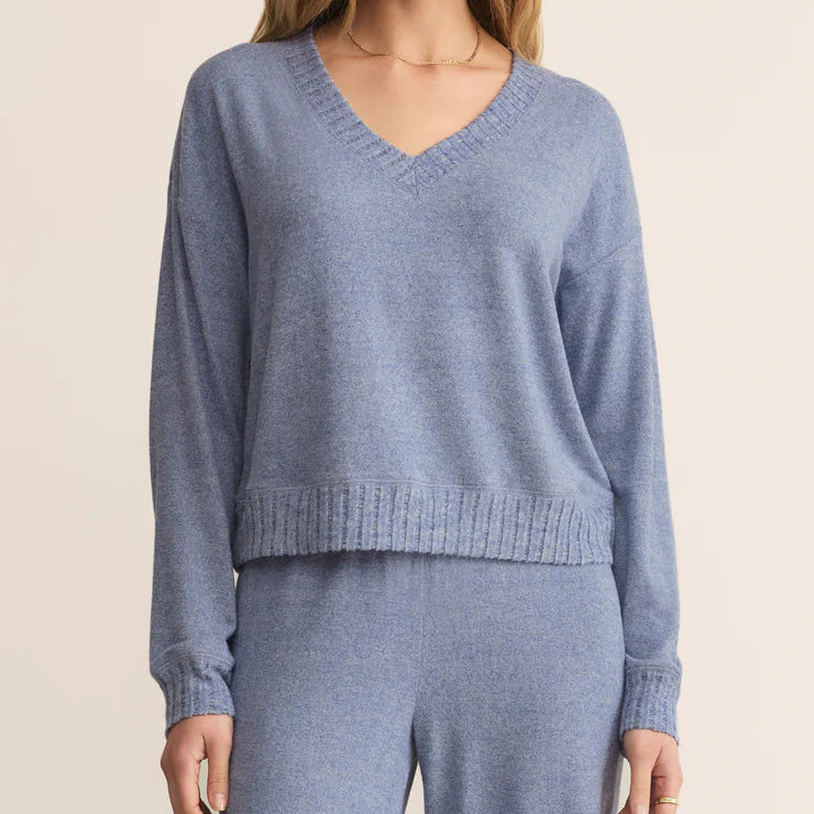 Woman wearing a blue sweater and pants on a beige background