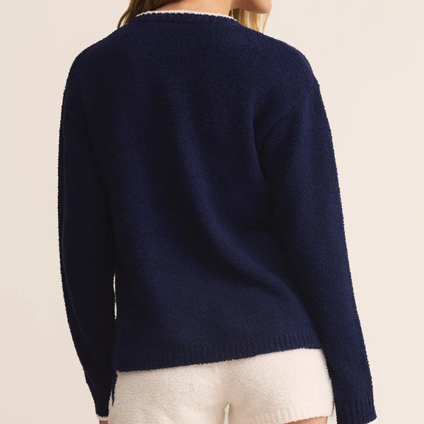 Woman wearing a navy sweater and white shorts on a beige background