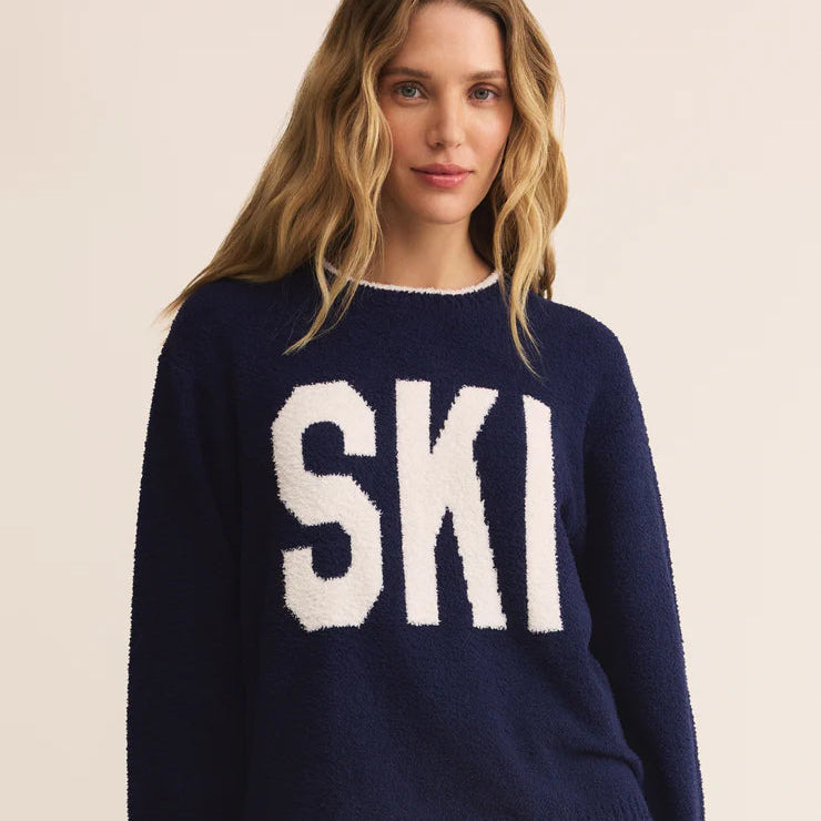 Woman wearing a navy blue sweater with 'SKI' in white letters on a beige background