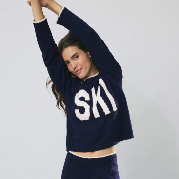 Person wearing a navy sweater with 'SKI' text on a white background