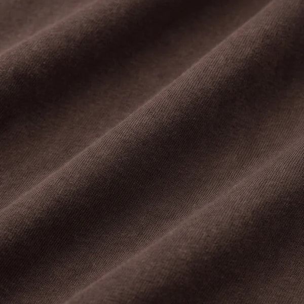 A close-up of draped dark brown fabric with soft folds and a smooth texture.