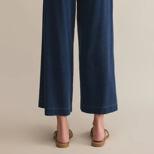 Navy blue wide-leg pants worn by a person on a beige background