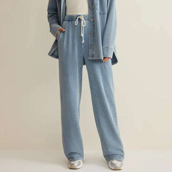 Woman wearing a denim outfit with a white top on a plain background