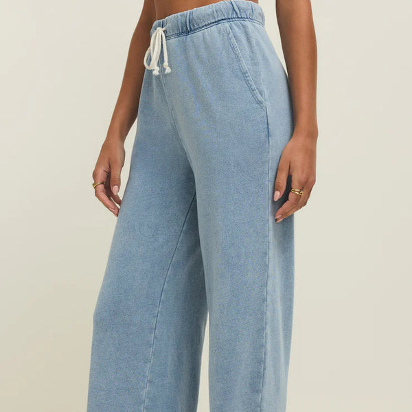Light blue wide-leg jeans worn by a person on a beige background