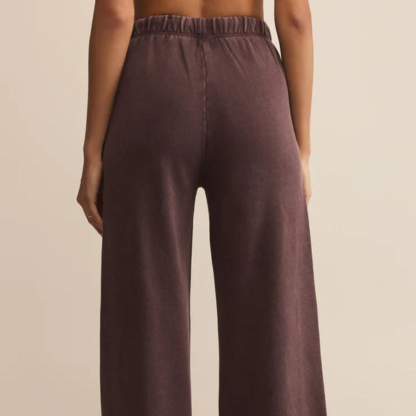Brown wide-leg pants worn by a person on a beige background