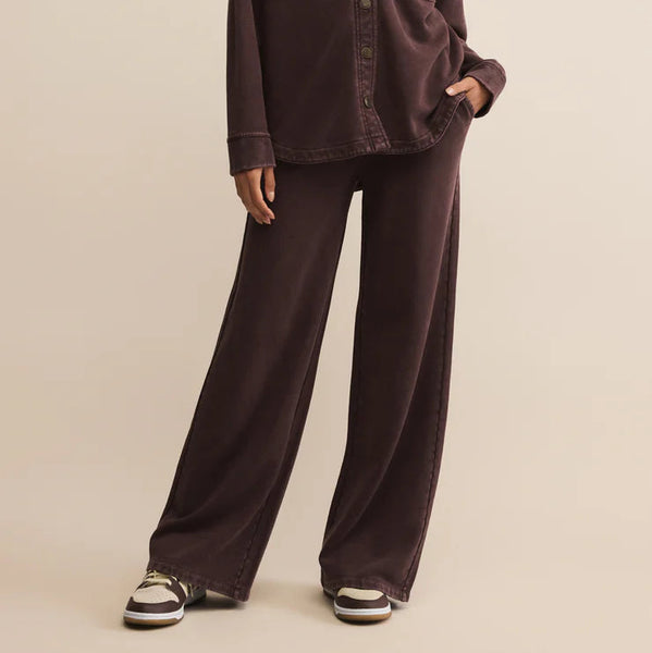 Woman wearing a brown shirt and pants on a beige background