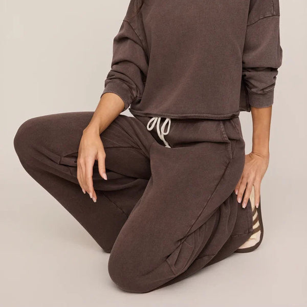 Woman wearing a brown outfit sitting on a white background