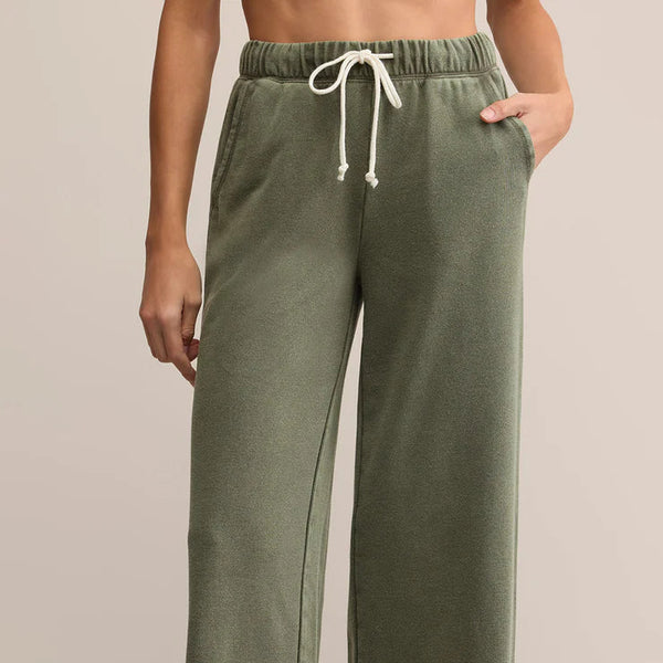 Person wearing olive green wide-leg pants with a drawstring waist on a beige background