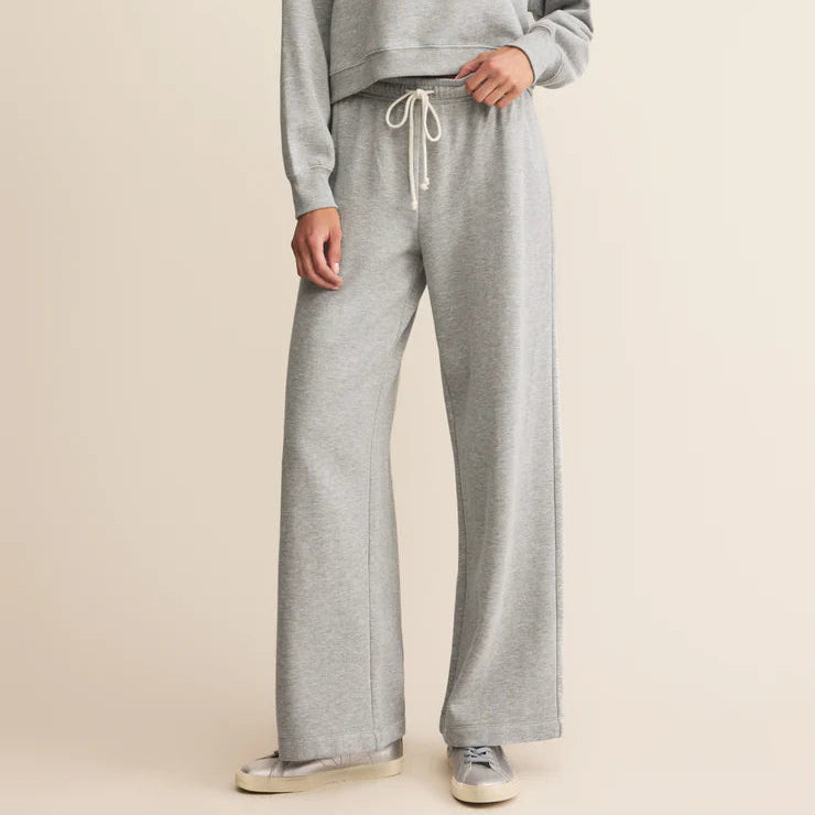 Woman wearing a gray sweatshirt and pants on a beige background