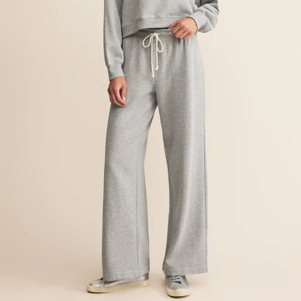 Woman wearing a gray sweatshirt and pants on a beige background