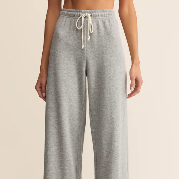 Person wearing gray sweatpants with a beige background