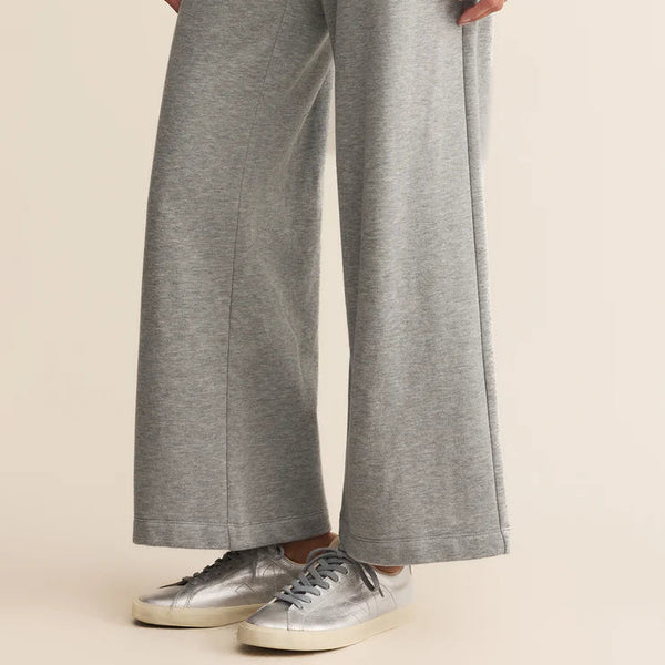 Person wearing gray wide-leg pants with a beige background