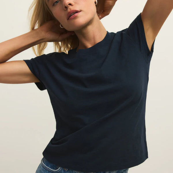 Woman wearing a navy blue t-shirt and blue jeans against a plain background