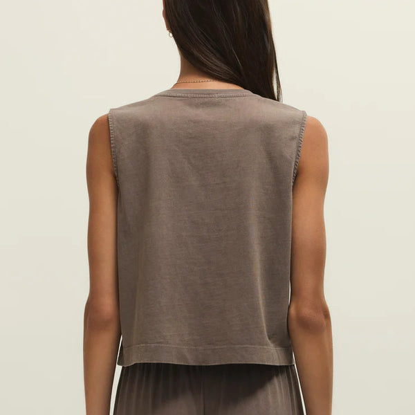 Woman wearing a brown sleeveless top and pants on a beige background